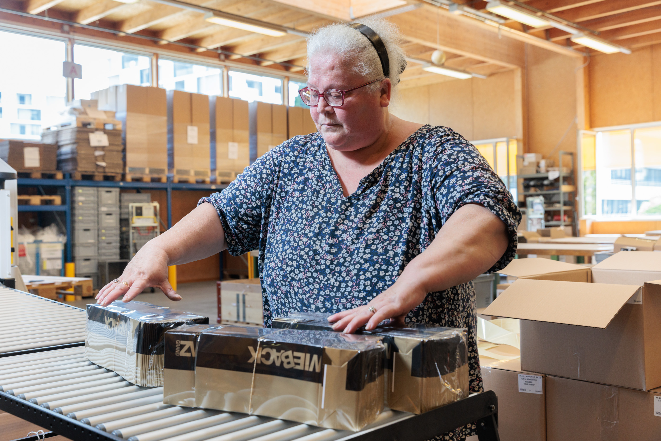 Femme qui conditionne des emballages sous film plastique