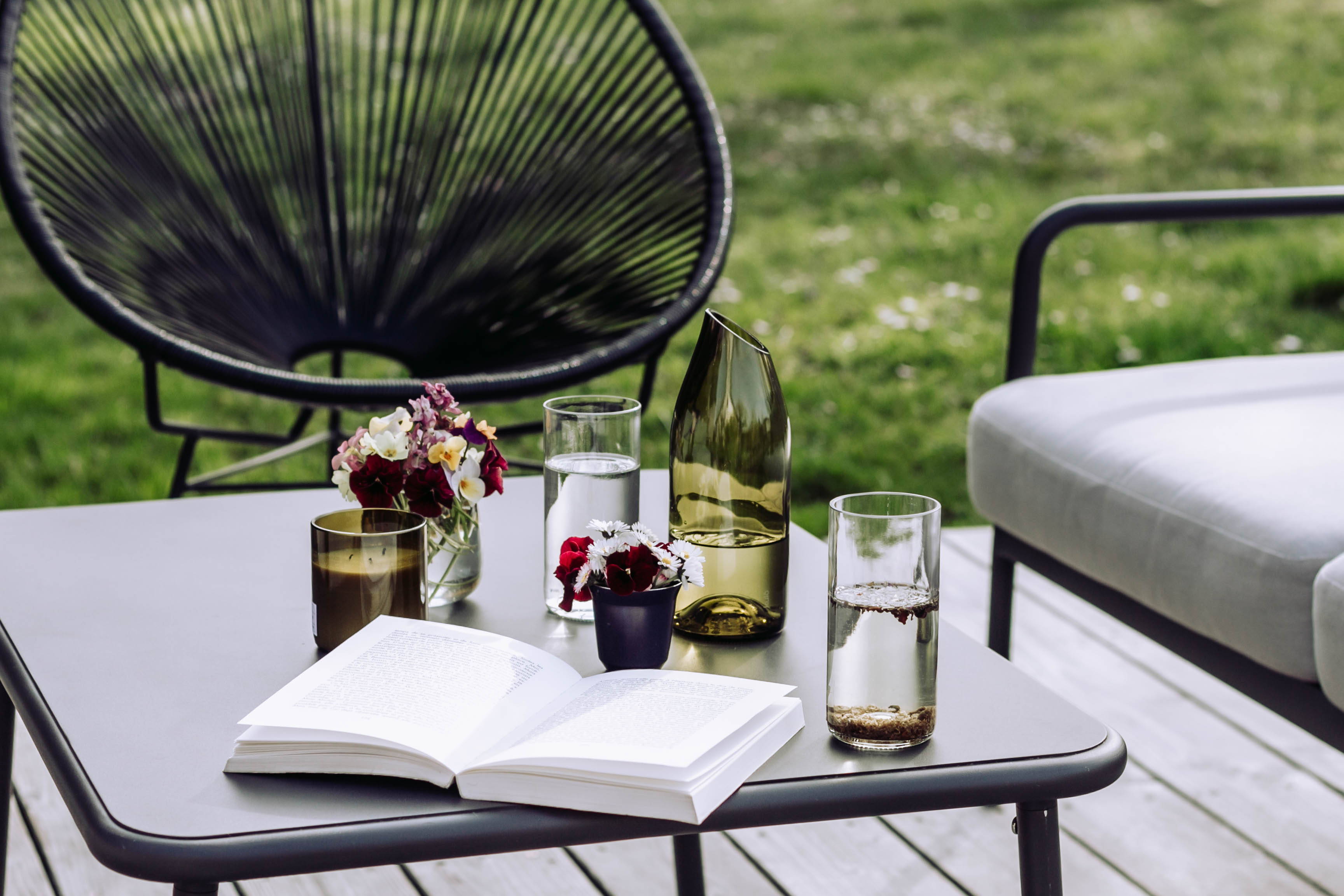 Verres et carafe de la marque kulô posés sur une table de jardin.